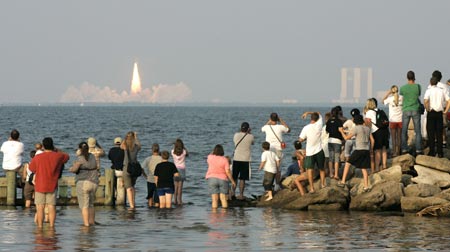 Crowds of people in Titusville, Florida watch the space shuttle Endeavour as it launches from the Kennedy Space Center in Cape Canaveral, Florida on August 8, 2007. Endeavour blasted off on Wednesday for a construction mission to the International Space Station, carrying a former teacher who first trained for space flight with the ill-fated Challenger crew. 