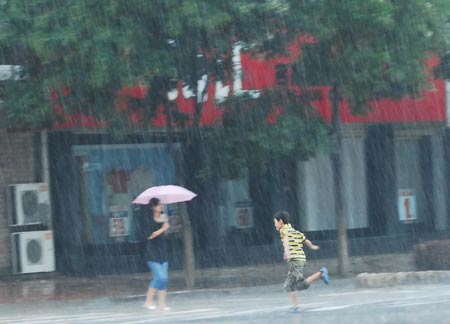 A boy runs in rain in Yantai, East China’s Shandong Province, August 10, 2007. [Xinhua]