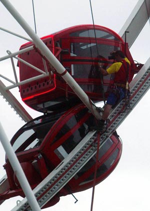 Fire fighters rescue people at a travelling theme park set up in a town in the southern port city of Busan, about 450 km (280 miles) southeast of Seoul, August 13, 2007. Four South Koreans including a child were killed on Monday when a door to their gondola on a 60-metre (55 yard)-tall Ferris wheel came unlocked and swung open, pouring them to the ground, police officers said.[Xinhua]