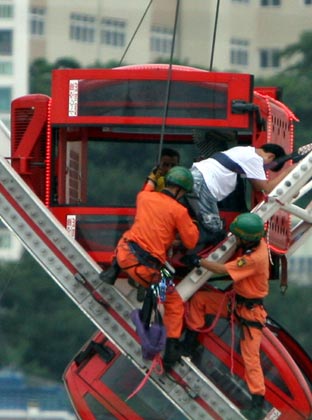 Fire fighters rescue people at a travelling theme park set up in a town in the southern port city of Busan, about 450 km (280 miles) southeast of Seoul, August 13, 2007. Four South Koreans including a child were killed on Monday when a door to their gondola on a 60-metre (55 yard)-tall Ferris wheel came unlocked and swung open, pouring them to the ground, police officers said. 