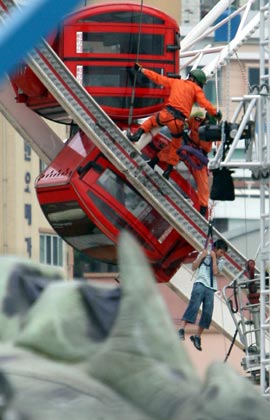 Fire fighters rescue people at a travelling theme park set up in a town in the southern port city of Busan, about 450 km (280 miles) southeast of Seoul, August 13, 2007. Four South Koreans including a child were killed on Monday when a door to their gondola on a 60-metre (55 yard)-tall Ferris wheel came unlocked and swung open, pouring them to the ground, police officers said. 