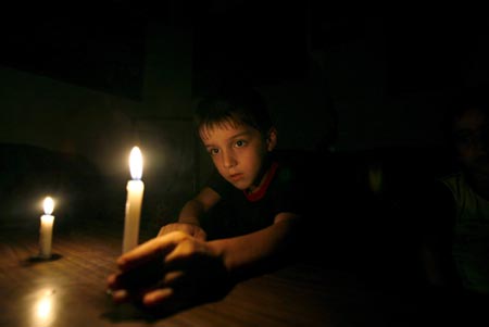 A Palestinian boy lights candles during a power cut in Gaza city August 18, 2007. Israel plans to open a Gaza Strip crossing for several hours to let fuel be transported to the territory, the army said on Saturday, a day after power generators there shut down due to a fuel blockade. 
