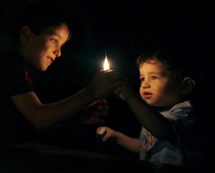 Palestinian children hold a candle during a power cut in Gaza city August 18, 2007. Israel plans to open a Gaza Strip crossing for several hours to let fuel be transported to the territory, the army said on Saturday, a day after power generators there shut down due to a fuel blockade. 