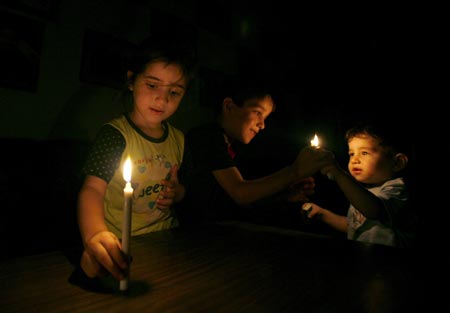 Palestinian children hold candles during a power cut in Gaza city August 18, 2007. Israel plans to open a Gaza Strip crossing for several hours to let fuel be transported to the territory, the army said on Saturday, a day after power generators there shut down due to a fuel blockade. 