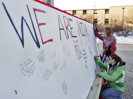 Students Michelle Nendza and Bailey Ouellette sign a wall in memory of the shooting victims at the Northern Illinois University campus in DeKalb, Illinois February 15, 2008. Steven Kazmierczak, 27, fired into a lecture hall packed with students at the university on February 14, killing six people and wounding 18 before killing himself. [Agencies]