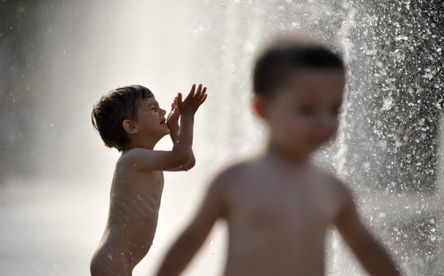 Naked children play with water in fountains at the Palace of Nations 