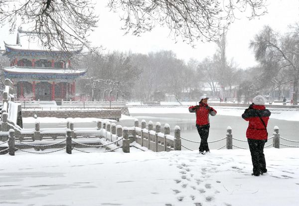 Residents take photos in the snow at a park in downtown Urumqi, capital of Northwest China's Xinjiang Uygur autonomous region, April 4, 2011. Heavy snow hits Urumqi