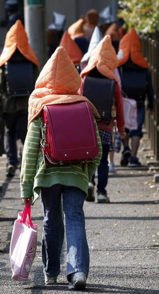 Elementary schoolchildren wear protective headgear as they walk to school in Tokyo April 25, 2011. Some schools in Tokyo have asked their students to wear the protective headgear on their way to school and while returning home since March 11's deadly earthquake and tsunami. Protective headgear for school children in Tokyo