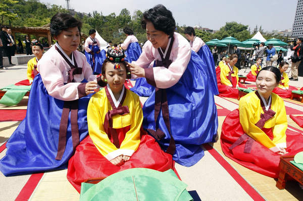 Women assist a participant with the donning of a traditional bride's headpiece during a coming-of-age ceremony in Seoul May 16, 2011. Coming-of-age day ceremony in Seoul