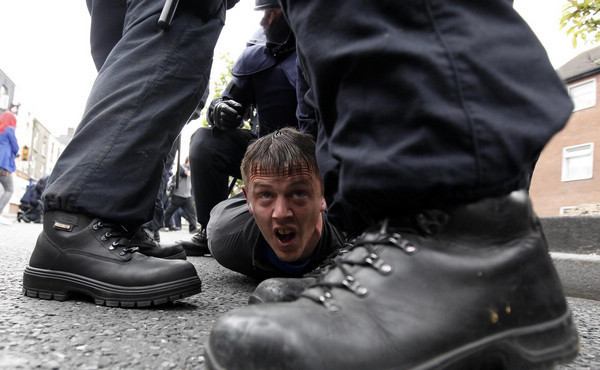 A man is detained by riot police during demonstrations in north Dublin May 17, 2011. Britain's Queen Elizabeth begins a four day state visit to Ireland today which is the first state visit by a British monarch since Ireland's independence. Queen's visit to Ireland prompts violent clashes