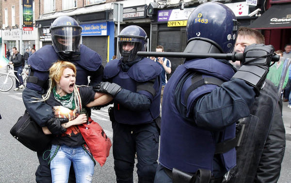 A woman is detained by riot police during disturbances in north Dublin May 17, 2011. Britain's Queen Elizabeth begins a four day state visit to Ireland today which is the first state visit by a British monarch since Ireland's independence. Queen's visit to Ireland prompts violent clashes