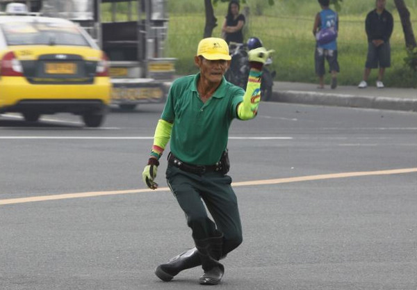 A combination picture shows Ramiro Hinojas, 46, a dancing traffic cop giving directions to vehicles along a busy street of Manila June 10, 2011. Dancing traffic cop