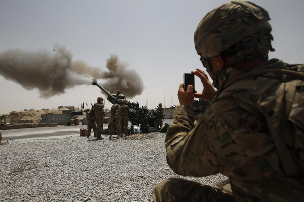 A US Army soldier from the 2nd Platoon, B battery 2-8 field artillery, takes a picture of a howitzer artillery piece being fired at Seprwan Ghar Forward fire base in Panjwai district, Kandahar province in southern Afghanistan, June 12, 2011. US soldiers fire howitzers in S Afghanistan