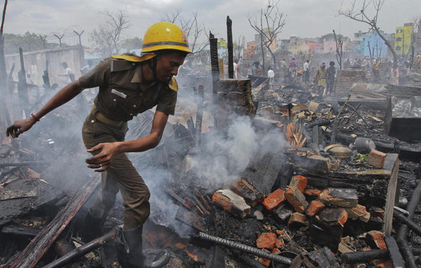 A firefighter goes through the debris in the aftermath of a fire which destroyed hundreds of dwellings at the Tondiapet slum in the southern Indian city of Chennai June 17, 2011. About 300 huts were gutted in the fire but no casualties were reported, a fire official said on Friday. The cause of the fire was unknown. Fire guts 300 huts in India