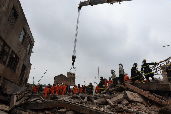Firefighters look for signs of life in the rubble of a building that collapsed in Huishan district, Wuxi, Jiangsu province, on Sunday morning, June 19, 2011. The collapse buried 16 people. Six of them were treated in hospital. The cause of the accident is being investigated. Building collapse buries 16 in East China city