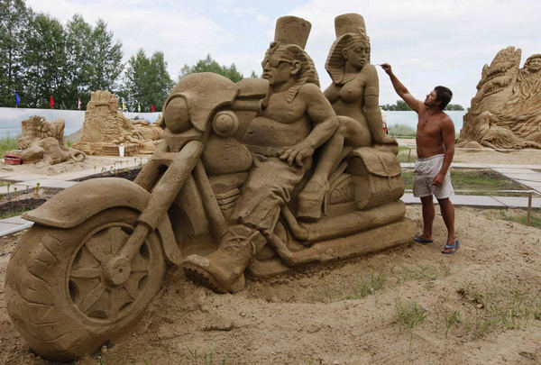 A park employee fine-tunes a sand sculpture called 'The Egyptian bikers' at a park in Russia's Siberian city of Krasnoyarsk, July 6, 2011. Sand sculptures in Russia's Krasnoyarsk