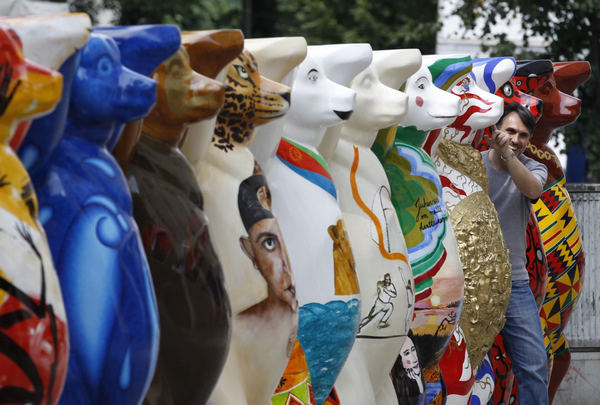 A tourist stands between Buddy Bear sculptures on Kurfuerstendamm Boulevard in Berlin July 12, 2011. Buddy Bear sculptures on displayed in Berlin