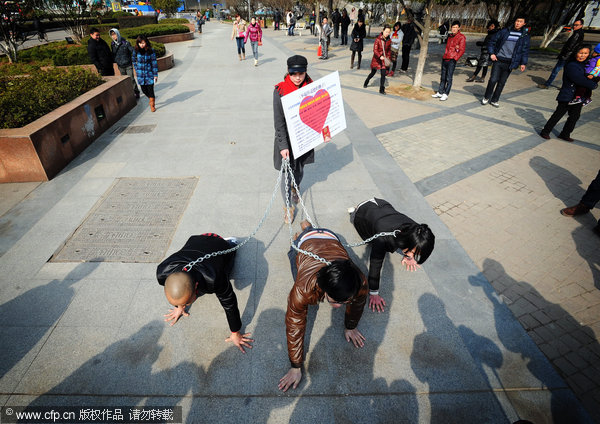 Three men crawl on the ground while chained by a woman during a publicity stunt in Wuhan, capital of Central China’s Hubei province, on Wednesday. Weekly Photos: Feb 6 - 12