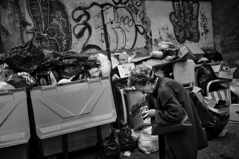 A woman place coins in her purse as she walks in front of containers full of garbage in Madrid, Nov 20, 2012. This week garbage collectors have been on strike for boycotting layoffs. One in four people in Spain are now unemployed as the economic crisis tightens its grip. The government is under pressure to seek aid to ease debts while the country sinks into its second recession in three years. Spain has raised nearly $6.4 billion in a successful debt auction that saw strong demand as the country holds off on seeking international help to manage its finances. Economy, Science and Technology News Stories Bronze Award