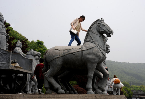 A tourist climbs on a statue in Wuxi, Jiangsu province, on May 10, 2013. Uncivilized behavior by Chinese tourists
