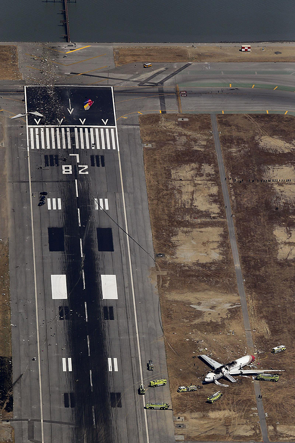 An aerial view shows rescue officials near an Asiana Airlines Boeing 777 plane after it crashed while landing at San Francisco International Airport in California on July 6, 2013. The plane, with 307 people on board, crashed and burst into flames as it landed at San Francisco International Airport on Saturday after a flight from Seoul, and initial reports said two people were killed and more than 130 sent to hospitals. After approaching the airport across San Francisco Bay, the plane appeared to strike the edge of the approach area of the runway. The tail came off and the aircraft left a trail of debris before coming to rest beside the runway. Asiana flight crashes at SFO