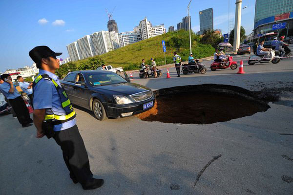 Sinkhole blocks road, damages 2 cars