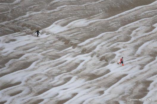 Tourists enjoy snow scenery in Dunhuang's desert