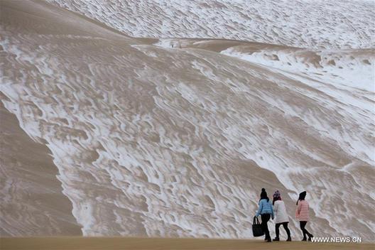 Tourists enjoy snow scenery in Dunhuang's desert