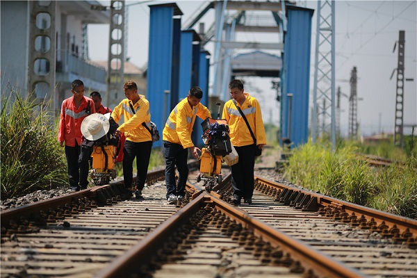 Workers carry out rail inspection under scorching heat