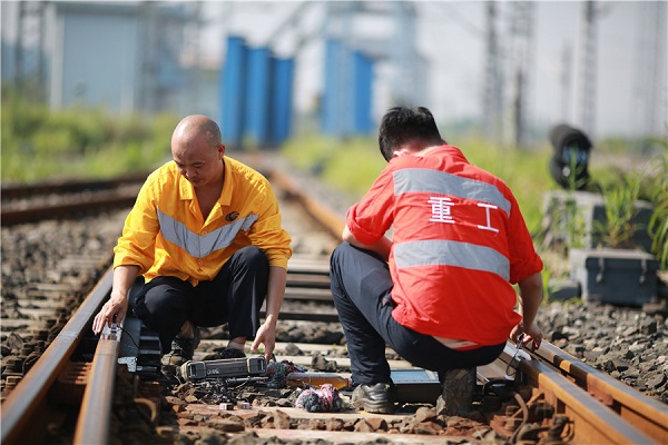 Workers carry out rail inspection under scorching heat