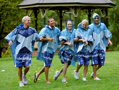Swimming team members from Scotland (L-R) David Carry, Gregor Tait, Kirsty Balfour, Caitlin McClatchey and Todd Cooper walk in the rain before a media conference in Melbourne March 13, 2006. The Commonwealth Games are being held in Melbourne from March 15 to 26. [Reuters]