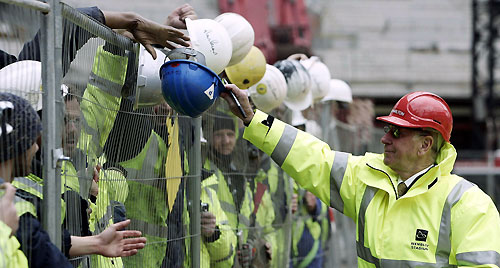 Former England soccer player Bobby Charlton signs builders' hats during a visit to Wembley Stadium in London March 21, 2006.