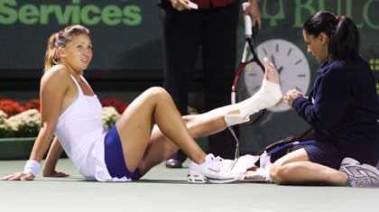 Tatiana Golovin of France has her ankle tended to by medical staff after an injury in the third set of her semi final against Maria Sharapova of Russia at the Nasdaq-100 Open tennis tournament in Key Biscayne, Florida March 30, 2006. Golovin withdrew from the match.