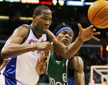 Los Angeles Clippers Elton Brand (L) loses the ball as he is fouled by Dallas Mavericks Marquis Daniels during the second half of NBA basketball action in Los Angeles April 10, 2006. The Mavericks won 75-73.