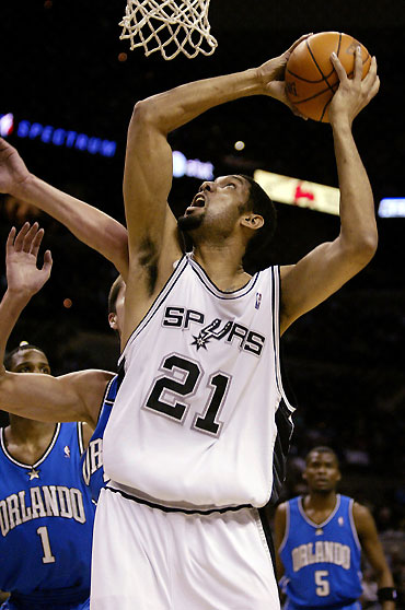 Antonio Spurs forward Tim Duncan (C) goes to the basket against Orlando Magic forward Trevor Ariza (L) a