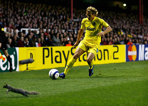 squirrel runs off the pitch as Villarreal's Diego Forlan crosses the ball during the Champions League first leg
