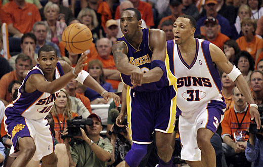 Los Angeles Lakers guard Kobe Bryants (C) passes while being guarded by Phoenix Suns guard Leandro Barbosa (L) and forward Shawn Marion during fourth quarter action in Game One of their first round NBA Western Conference playoff game in Phoenix, Arizona April 23, 2006.