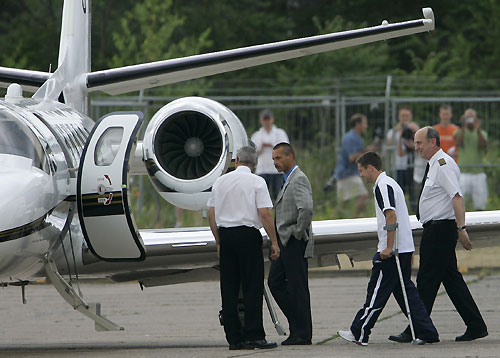 England's soccer star Michael Owen (2R) with pilots and security men walks to his plane at the airport in Baden-Baden June 21, 2006, after he was injured during the World Cup 2006 soccer match against Sweden on Tuesday. 