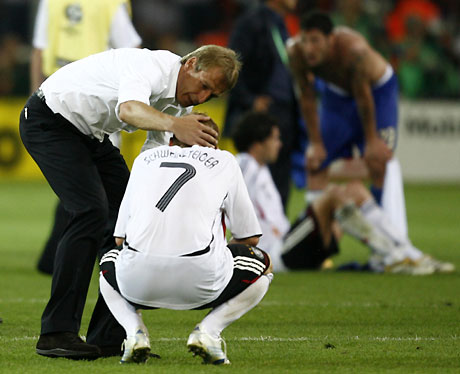 Germany coach Juergen Klinsmann (L) consoles Germany's Bastian Schweinsteiger after their World Cup 2006 semi-final soccer match against Italy in Dortmund July 4, 2006.