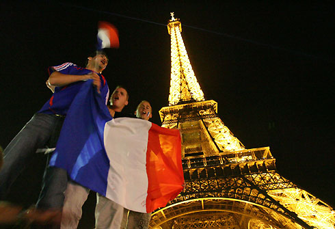 France soccer team supporters carry a French flag in front of the Eiffel tower in Paris after France defeated Portugal in the semi-final of the soccer World Cup 2006, July 5, 2006.