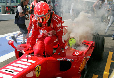 German Formula One driver Michael Schumacher leaves his Ferrari as it catches fire during the third practice session of the French Grand Prix at the Magny-Cours circuit July 15, 2006.