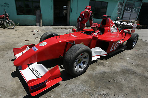 A vehicle drives past a homemade model of Formula One car in Tangshan, Hebei Province, some 180km (113 miles) east of Beijing July 21, 2006. Brothers Zhao Xiushun and Zhao Xiuguo, who built the car from scrap metal, said they wanted to design and build the first Formula One racecar in China.