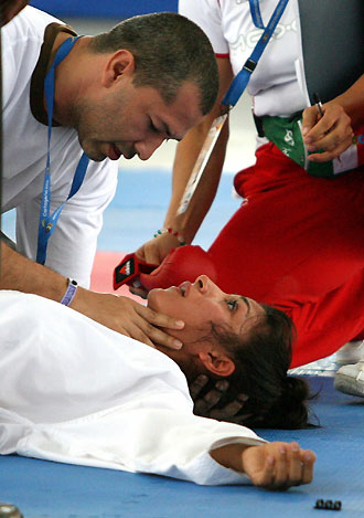 Bertha Gutierrez of Mexico is helped by a doctor after receiving a kick from Dominican Republic's Johnnys Sierras during the women's under 60kg-kumite of karate-do individual competition at the Central American and Caribbean Games in Cartagena, Colombia, July 24, 2006.