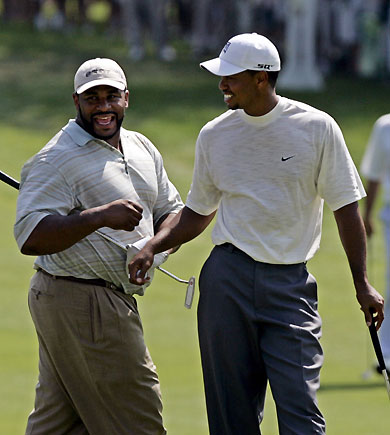 Former Super Bowl Champion Pittsburgh Steelers running back Jerome Bettis (L) laughs with Tigers Woods of the U.S. after Bettis shot the ball out of the rough during the Buick Open golf tournament in Grand Blanc, Michigan August 2, 2006.