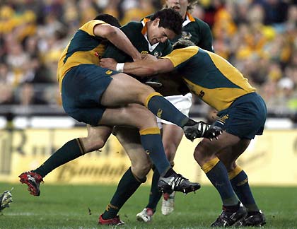 Australia's Mark Gerrard (L) and team mate Phil Waugh (R) tackle South Africa's Jaque Fourie during their Tri-Nations rugby union Test match in Sydney August 5, 2006. 