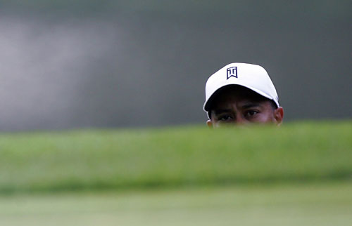 Tiger Woods watches a chip onto a green during the first day of practice for the 88th PGA Championship in Medinah, Illinois, August 14, 2006.