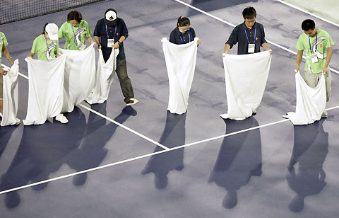 Workers dry the court with towels as the match between France's Amelie Mauresmo and Russia's Svetlana Kuznetsova was delayed because of rain during the final of the China Open tennis tournament in Beijing September 24, 2006.