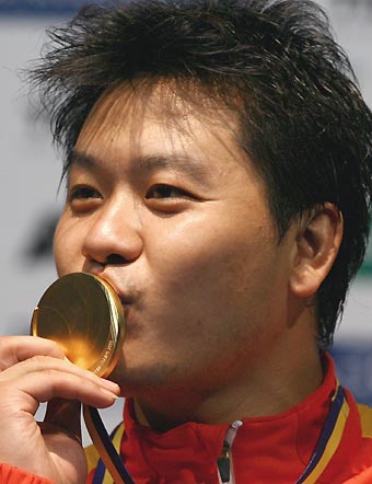 China's Wang Lei kisses the gold medal on the podium after defeating Portugal's Joaquim Videira to win the men's fencing individual epee event at the World Fencing Championship in Turin October 2, 2006.