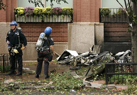 New York Police Department officers look at the debris near the site where a small aircraft crashed into a high-rise building in New York City October 11, 2006.