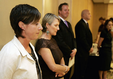 Tracey Menzies (L), coach of Australia's world and Olympic swimming champion swimmer Ian Thorpe, listens along with other supporters as Thorpe announces his retirement during a media conference in Sydney November 21, 2006. Thorpe told a packed news conference broadcast live on Australian television that he had decided to quit because swimming was no longer the most important thing in his life.